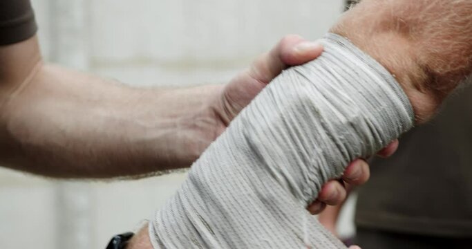 putting a compression bandage on the hand. a man puts a bandage on his hand, rewinding the fabric. providing first aid for injured hands. close-up