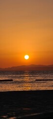 Vertical shot of a bright glowing sunset sky over a seashore