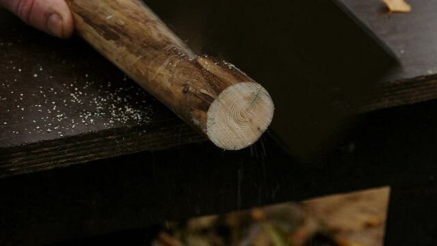 man sawing with a hand hacksaw close-up