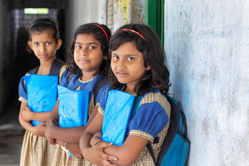 School Children's holding books standing at school