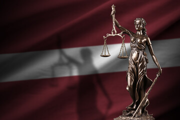Latvia flag with statue of lady justice and judicial scales in dark room. Concept of judgement and...