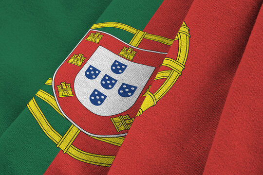 Portugal flag with big folds waving close up under the studio light indoors. The official symbols and colors in banner