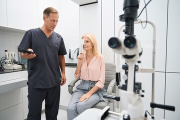 Fototapeta na wymiar Ophthalmologist standing near the patient and checking vision quality