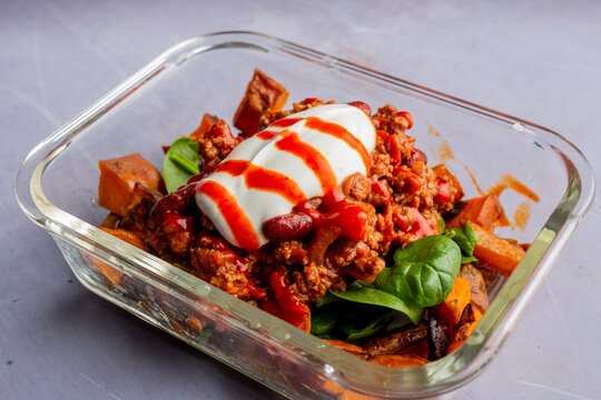 Tasty dish of minced meat, fresh spinach, squash served with red and white sauces in a pyrex