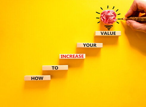 Increase your value symbol. Concept words How to increase your value on wooden blocks. Businessman hand. Beautiful yellow background. Business how to increase your value concept. Copy space.