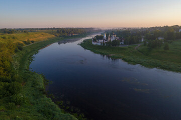 July dawn on the Volga river. View of the Staritstsa Holy Assumption Monastery (aerial photography). Tver region, Russia