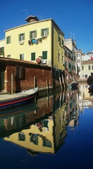 Fototapeta na wymiar Vertical shot of stone buildings and their reflections in the canal in Venice, Italy