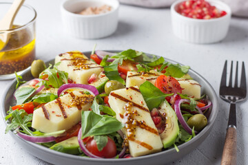 Salad with fried Halloumi cheese, cherry tomatoes, arugula and pomegranate seeds. healthy food.