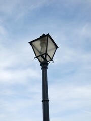 Fototapeta na wymiar Vertical shot of an old street light on blue cloudy sky background