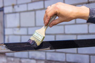 girl paint with a brush black metal. paints the roof.