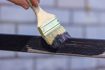 girl paint with a brush black metal. paints the roof.