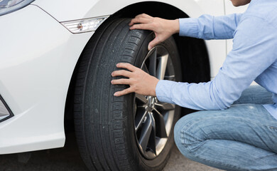 Close-up male automotive technician checking tires for tire inflation service at garage or gas...