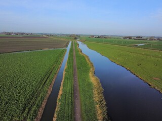 Beautiful scenery of a river flowing between green meadows in daylight in blue sky background