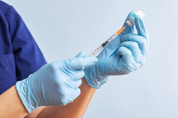 Doctor in blue gloves preparing syringe for injection. Vaccination concepts