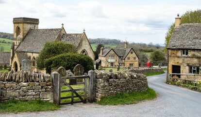 Road with cottages surrounded by rocky gates in Snowshill, Cotswold, England
