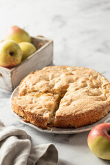 Charlotte apple cake with apples in wooden box and linen napkin on white marbel background, apple pie. Copy space