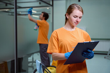 Cleaning copany employee following a checklist with her partner working