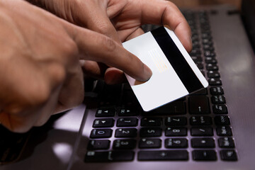 mano agarrando tarjeta de crédito y usando laptop o computadora. Concepto de compras por internet...