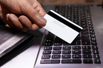 mano agarrando tarjeta de crédito y usando laptop o computadora. Concepto de compras por internet...
