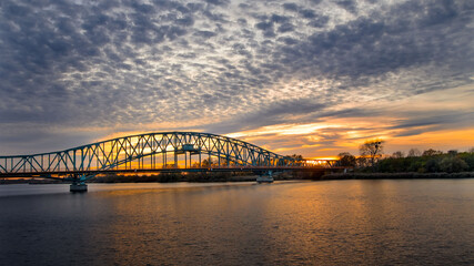 Naklejka premium Zachód słońca, nad rzeką w tle most.