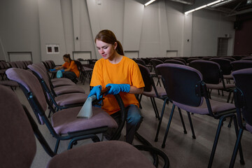 Two cleaning company workers sanitizing the chairs in sitting area