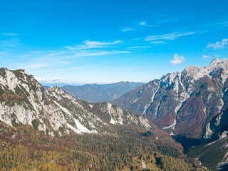 Aerial view of autumn trees near the rocky mountains under a bright sky in Vrsic, Slovenia