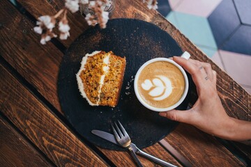 top view of a man's hand holding a cup of coffee on a wooden table