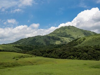 Green landscape with mountains and a cloudscape in the background