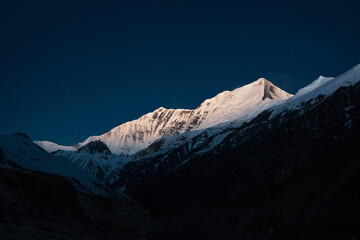 Witte besneeuwde bergen tegen een donkerblauwe lucht. Berglandschap in het Dhaulagiri-basiskamp, regio Myagdi, Nepal. Himalayagebergte na zonsondergang.