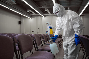 Responsible janitors using protective gear during disinfective procedures