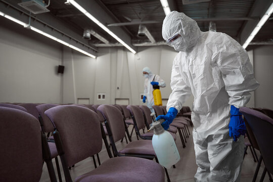 Responsible Janitors Using Protective Gear During Disinfective Procedures