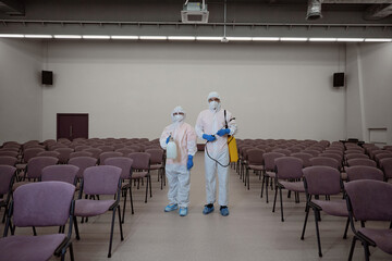Well-trained cleaners in protective gear standing in freshly-cleaned building