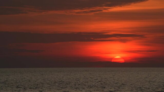 Sun set into the sea scape and dark cloud sky in 4K footage.