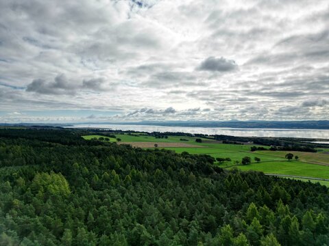 Aerial shot of the green Devilla Forest landscape in Scotland with a scenic cloudscape