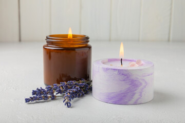Obraz na płótnie Canvas Aromatherapy concept, candle with lavender flowers.Soy candles with lavender scent. Candles on a white texture background. Place for text. Place for copying. Spa candles with a pleasant aroma.