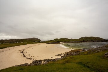 Fototapeta na wymiar Beautiful sandy beach next to the foamy waves of a sea on a gloomy day