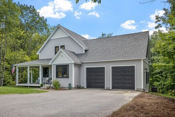 Modern custom new England colonial home with an American flag on a sunny day