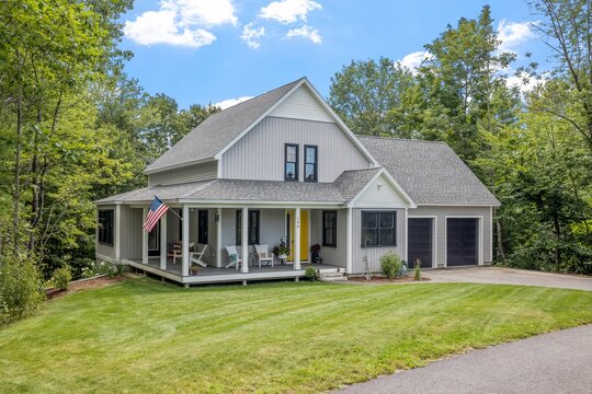 Modern custom new England colonial home with an American flag on a sunny day