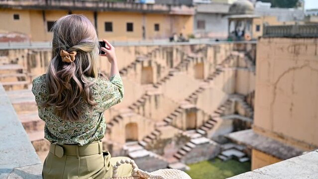 Asian woman taking picture of the Panna Meena ka Kund stepwell in Jaipur,
 Rajasthan