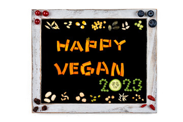 Happy Vegan 2023 written as seeds on slate.
