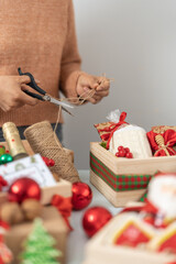 Person cutting string to prepare Christmas presents into boxes