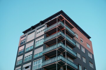 Closeup shot of a facade of a modern residential building with balconies against clear blue sky