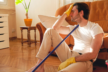 Handsome man holding vacuum cleaner and feel tired at the home - 545244636