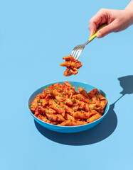 Penne pasta with spicy tomato sauce on a blue background.