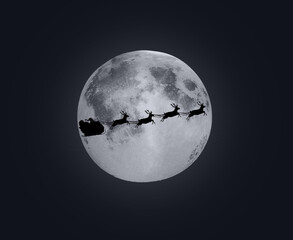 The shadow of Santa Claus rides in a sleigh through the moon.