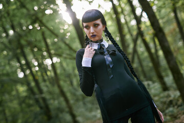 Dark goth girl standing in the forest, portrait of a wiccan witch performing magic