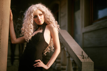 Portrait of a gothic girl, looking like a doll lolita, posing next to an old stone staircase of a castle or an old abandoned tower