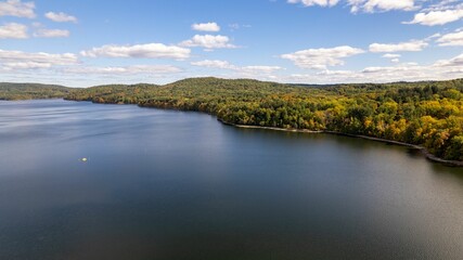 Drone shot of the water of New Croton Reservoir on a sunny day in autumn with a blue cloudy sky