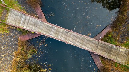 Aerial view of a wooden bridge over water in a park during the autumn season