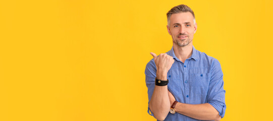 smiling mature man with hoary hair show thumb up on yellow background, copy space, pointing finger....